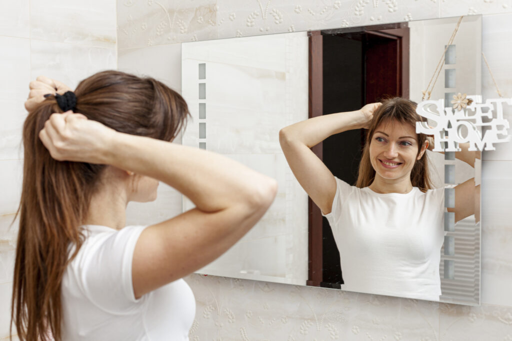 beautiful woman arranging her hair mirror
